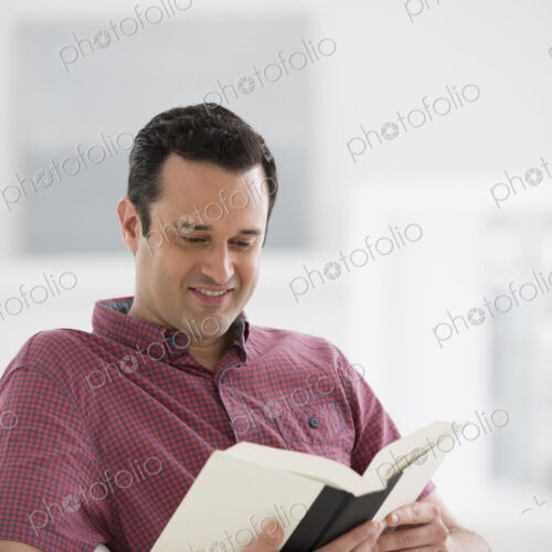 A bright white room interior. A man sitting reading a book. A bright white room interior. A man sitting reading a book.