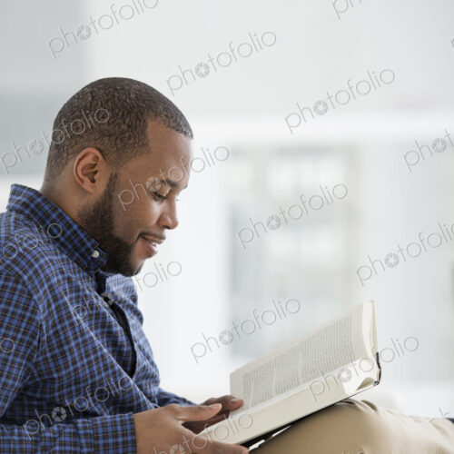 A bright white room interior. A man sitting reading a book. A bright white room interior. A man sitting reading a book.