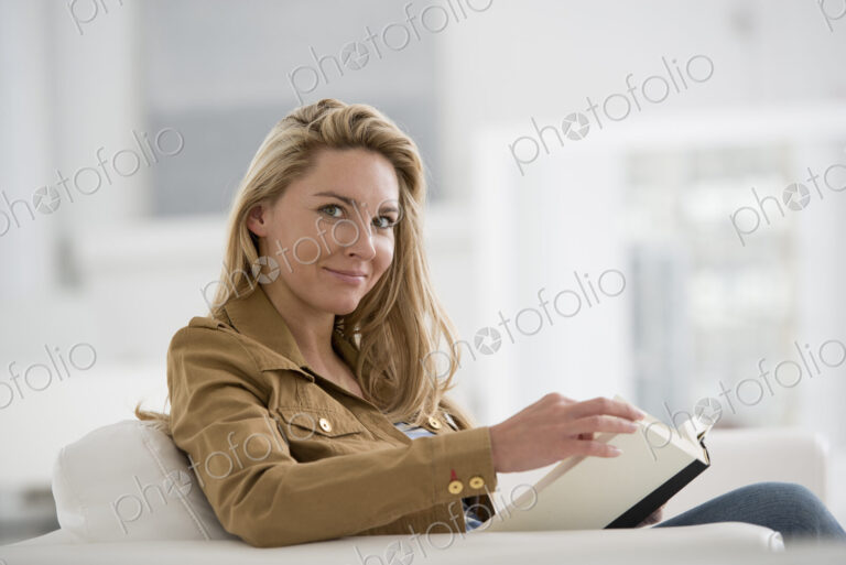 A bright white room interior. A woman sitting reading a book.