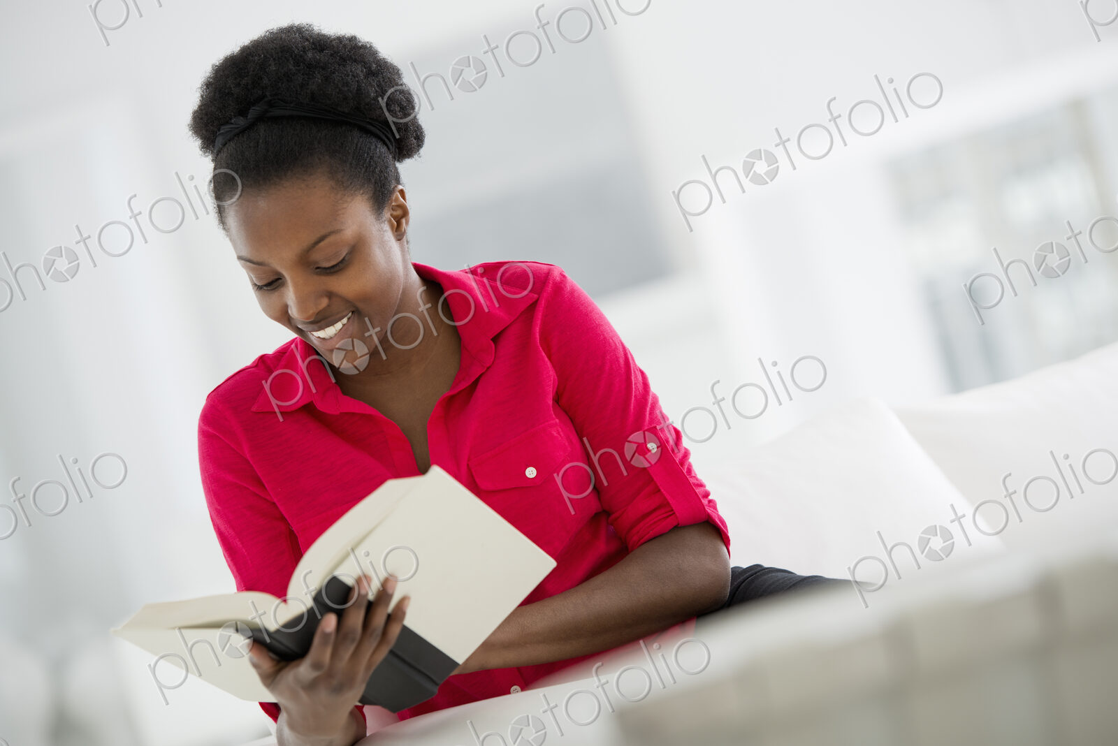 A bright white room interior. A woman sitting reading a book.