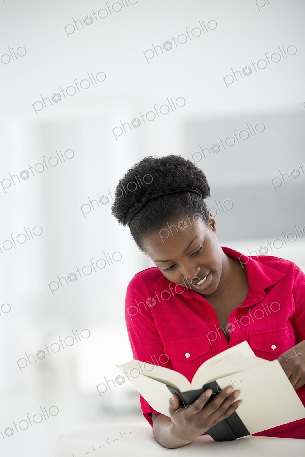 A bright white room interior. A woman sitting reading a book.