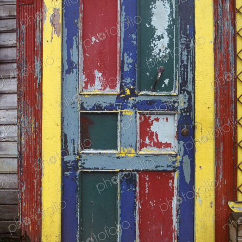 A bright worn painted door with red and blue panels and a yellow frame.