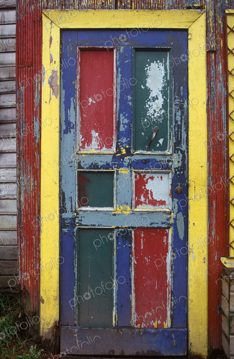 A bright worn painted door with red and blue panels and a yellow frame.
