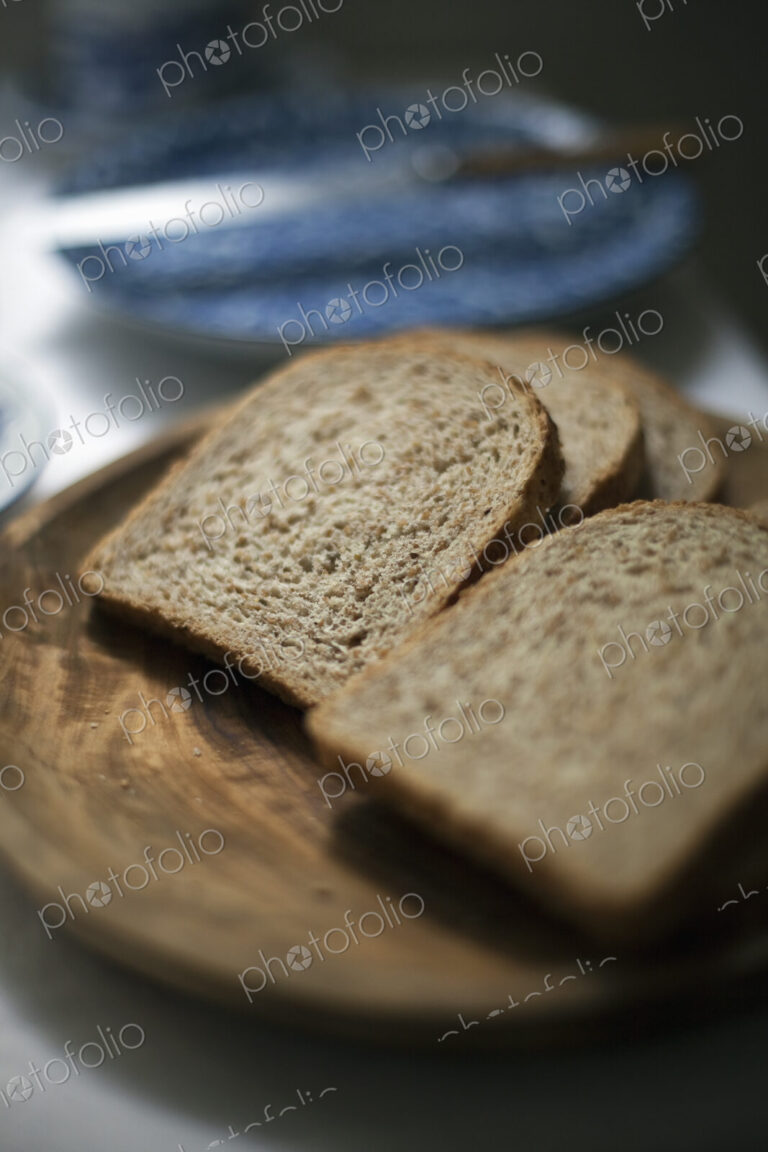 A buffet meal laid out. Sliced brown bread. A blue pate and knife.