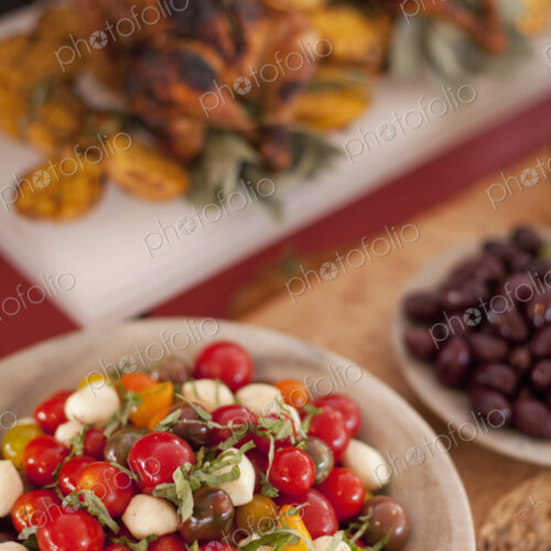 A buffet table laid out for a party. Organic food. Salads and a chicken dish.