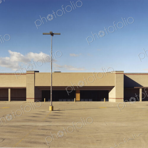 A building exterior, a single storey building with a large forecourt, carpark. A building exterior, a single storey building with a large forecourt, carpark.