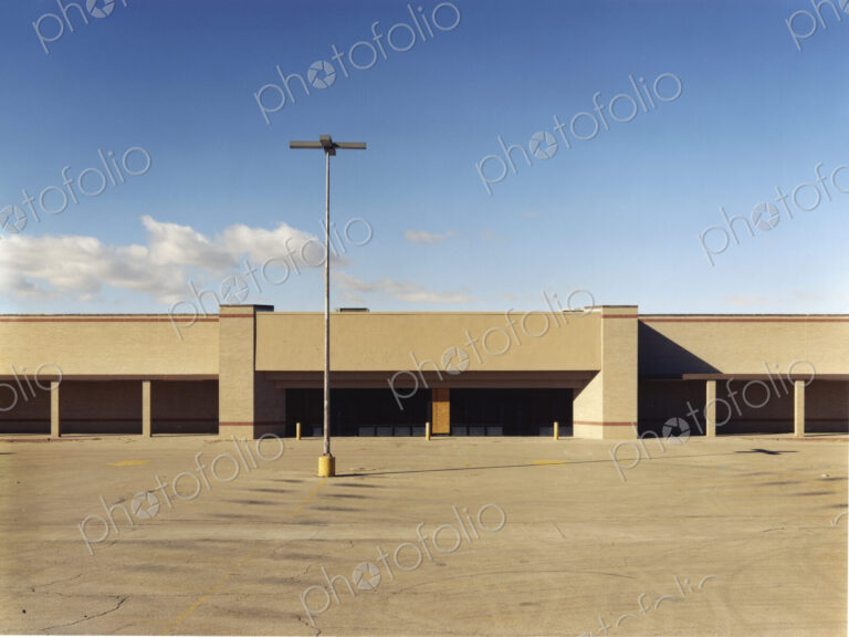 A building exterior, a single storey building with a large forecourt, carpark.