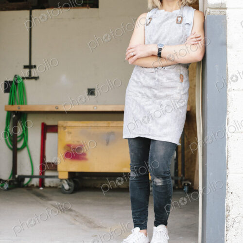 A business owner and craftsman standing in the doorway of her workshop.