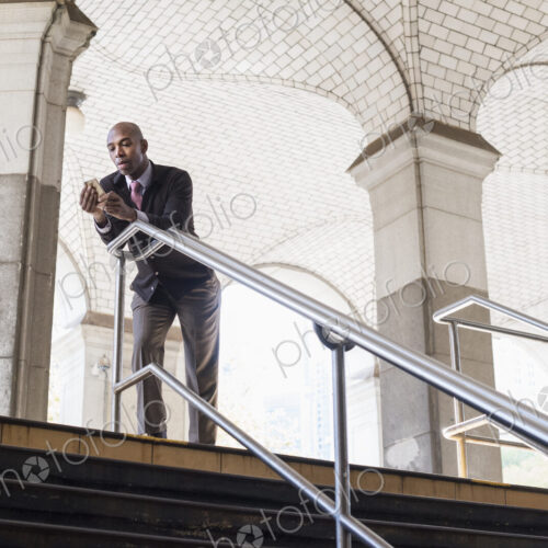 A businessman in a suit standing by a stairwell under an arched ceiling A businessman in a suit standing by a stairwell under an arched ceiling
