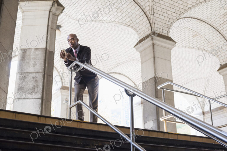 A businessman in a suit standing by a stairwell under an arched ceiling