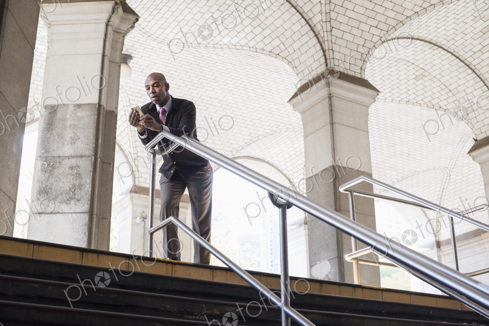 A businessman in a suit standing by a stairwell under an arched ceiling