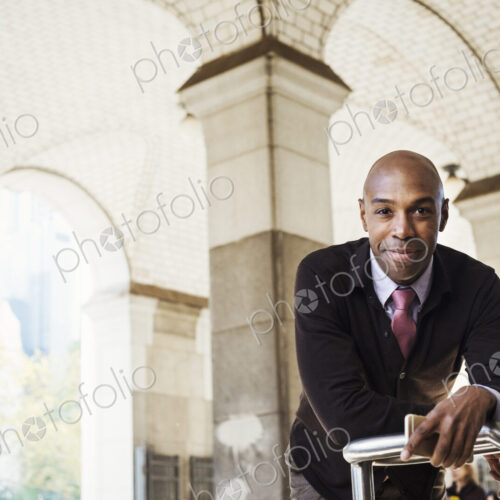 A businessman in a suit standing by a stairwell under an arched ceiling A businessman in a suit standing by a stairwell under an arched ceiling