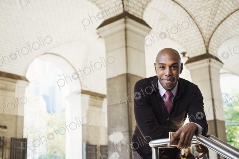 A businessman in a suit standing by a stairwell under an arched ceiling