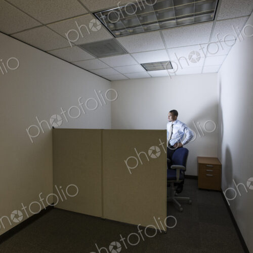A businessman lit up by a computer screen in his small corner office cubicle. A businessman lit up by a computer screen in his small corner office cubicle.