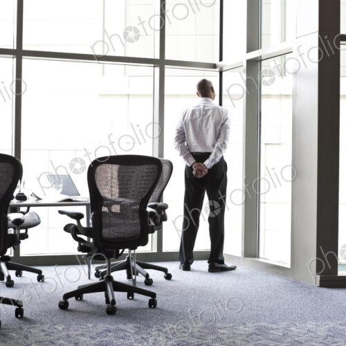 A businessman looking out the window at the city in the background.