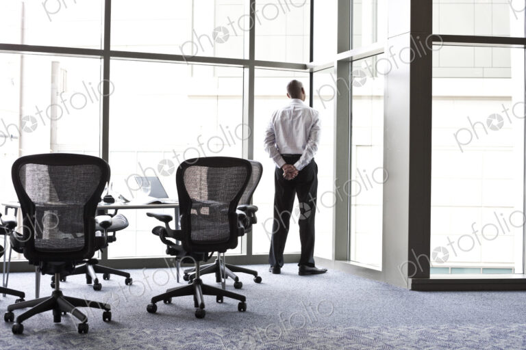 A businessman looking out the window at the city in the background.