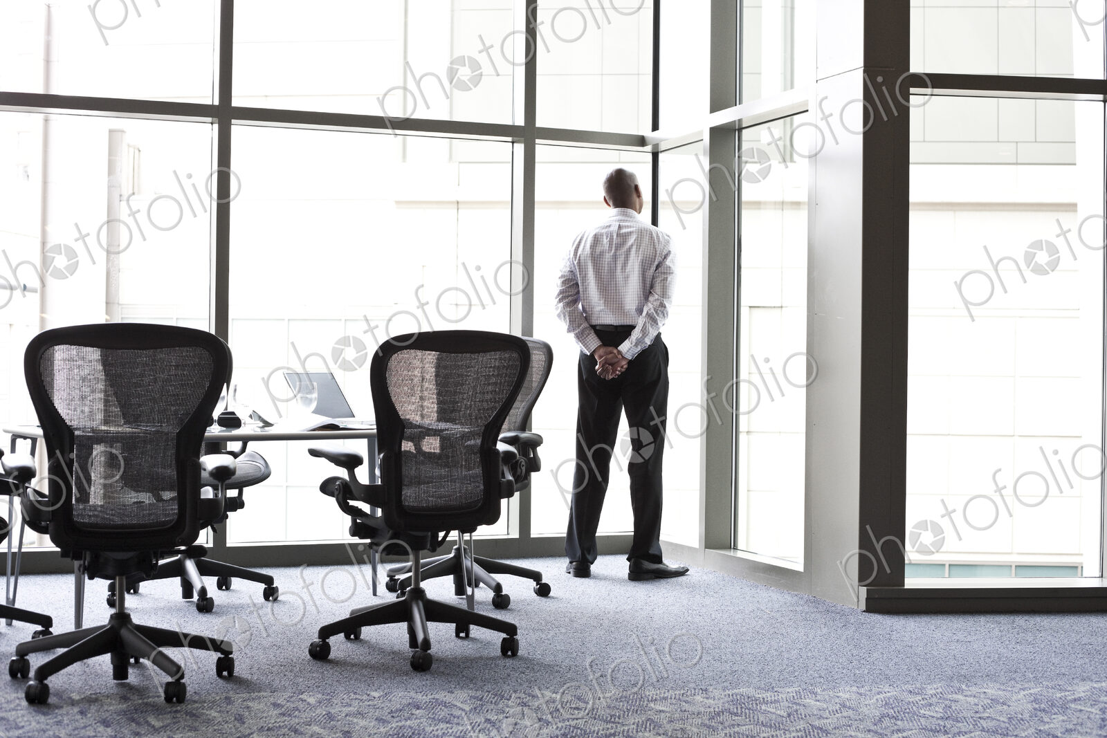 A businessman looking out the window at the city in the background.