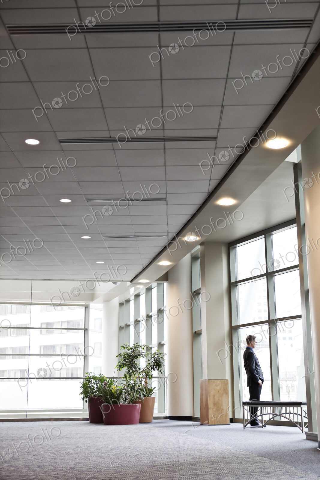 A businessman standing at a window in a large convention center lobby.