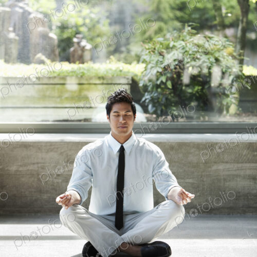 A businessman taking a meditative break in a room full of indoor plants. A businessman taking a meditative break in a room full of indoor plants.