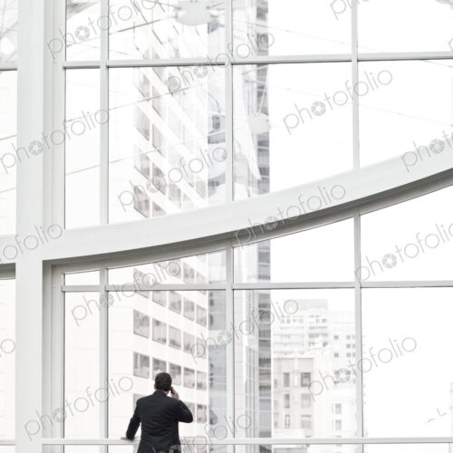 A businessman talking on a cell phone in a large convention center lobby. A businessman talking on a cell phone in a large convention center lobby.