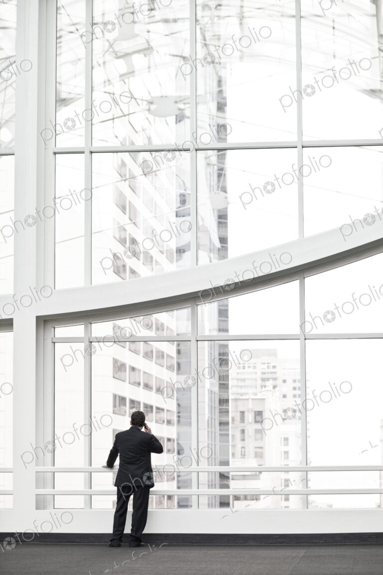 A businessman talking on a cell phone in a large convention center lobby.