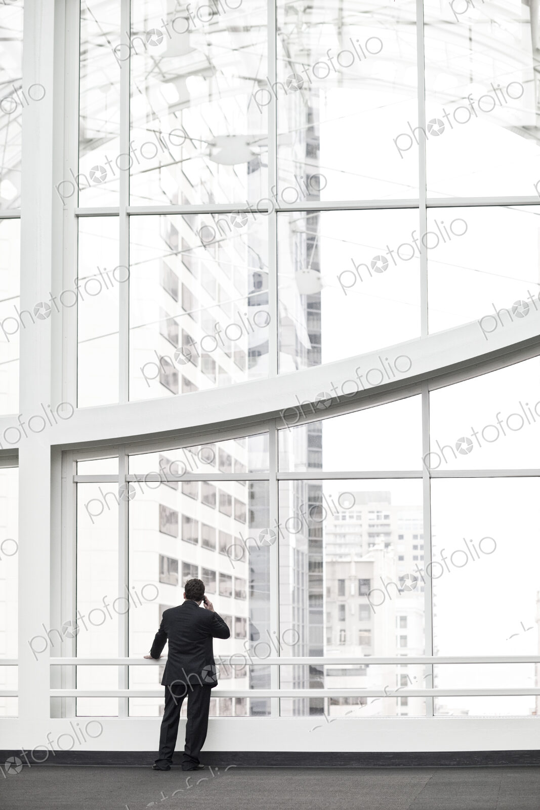 A businessman talking on a cell phone in a large convention center lobby.