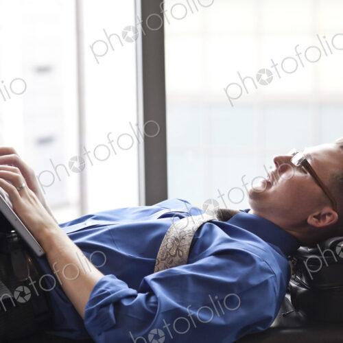 A businessman working on a laptop computer on a bench in a convention center lobby