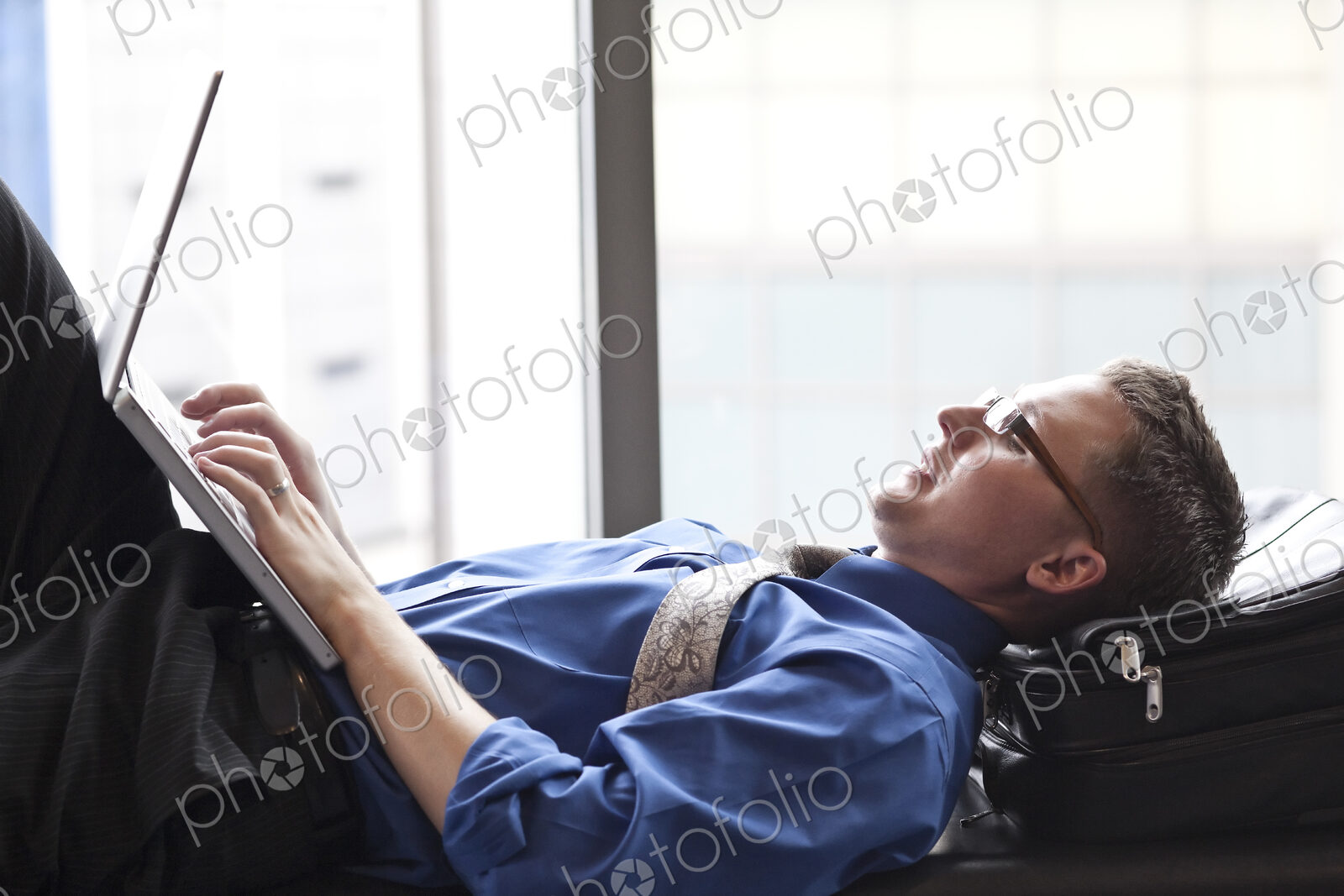 A businessman working on a laptop computer on a bench in a convention center lobby