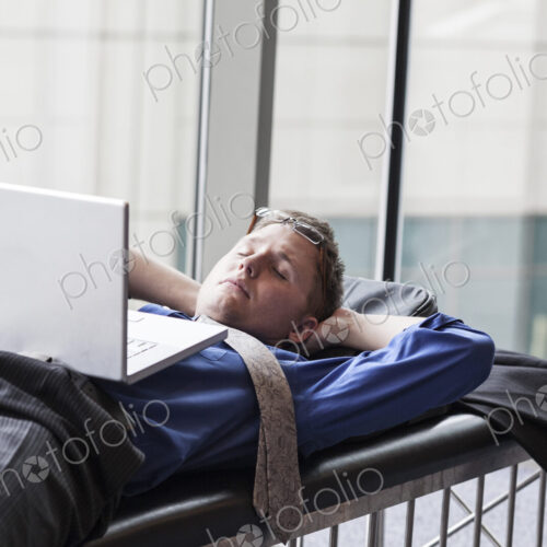 A businessman working on a laptop computer on a bench in a convention center lobby