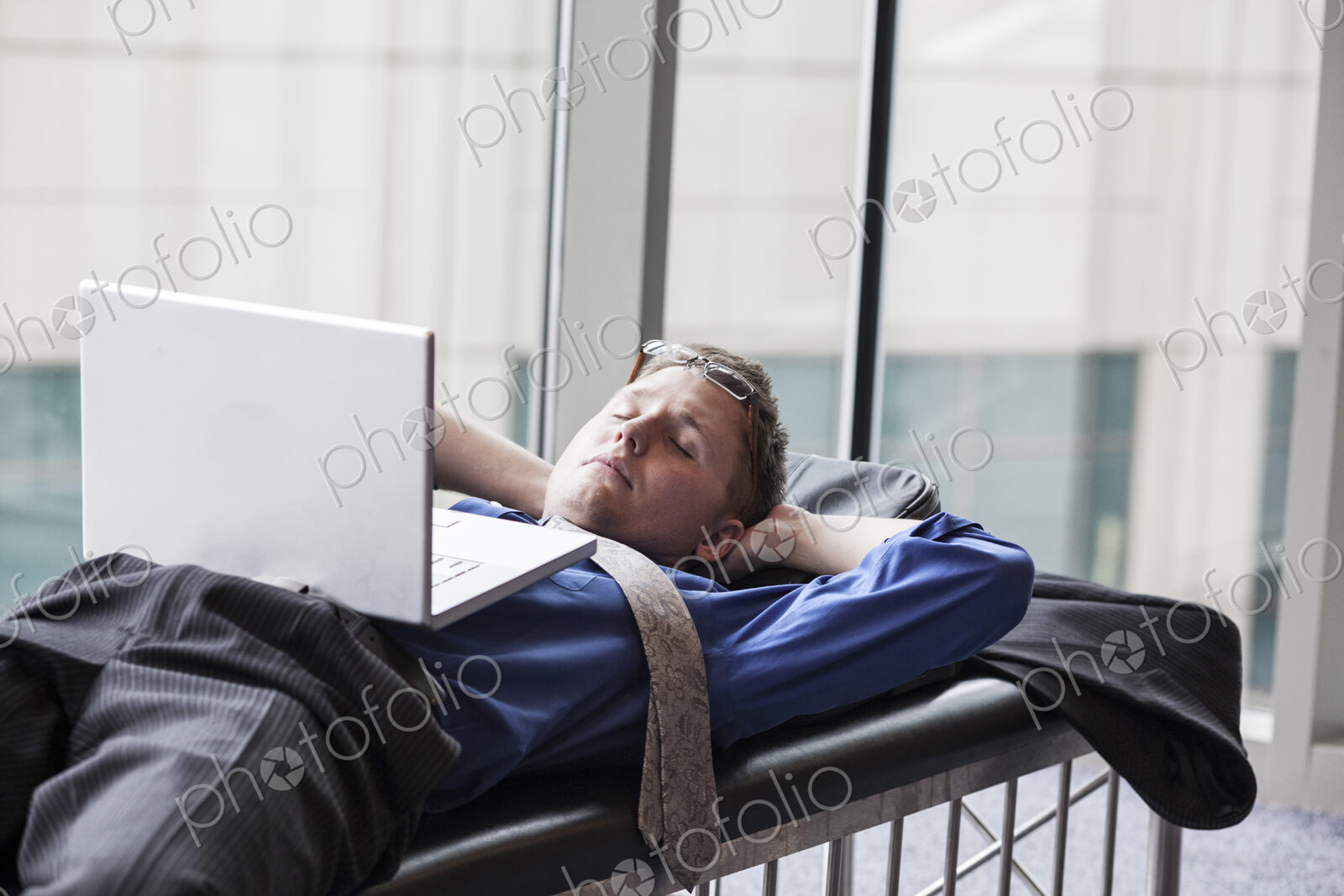 A businessman working on a laptop computer on a bench in a convention center lobby