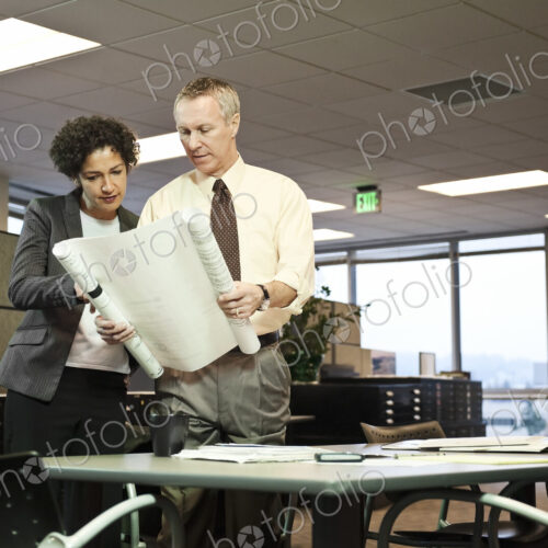 A businesswoman and a Caucasian businessman going over plans for a new office A businesswoman and a Caucasian businessman going over plans for a new office