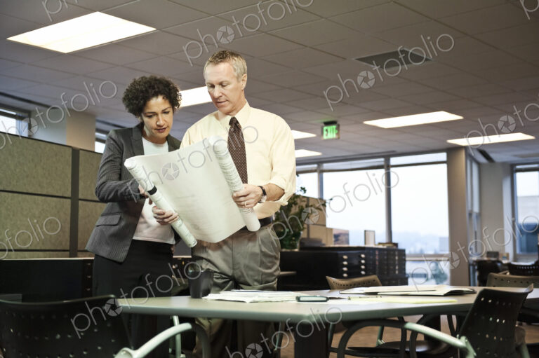 A businesswoman and a Caucasian businessman going over plans for a new office