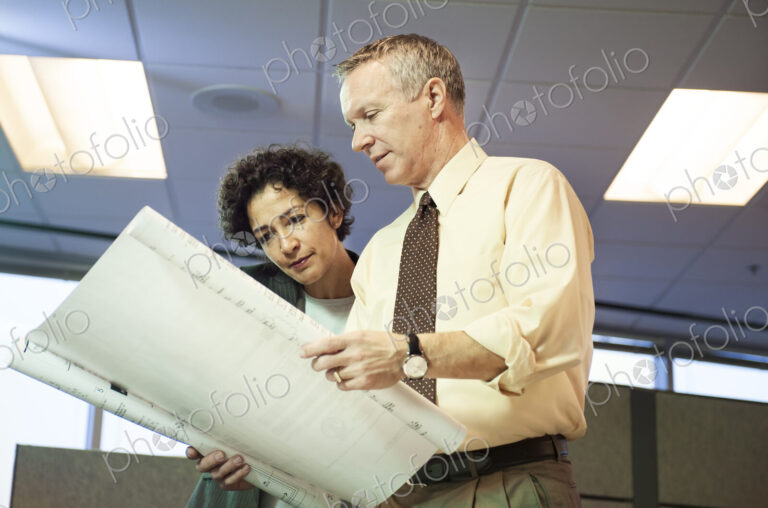 A businesswoman and a Caucasian businessman going over plans for an office