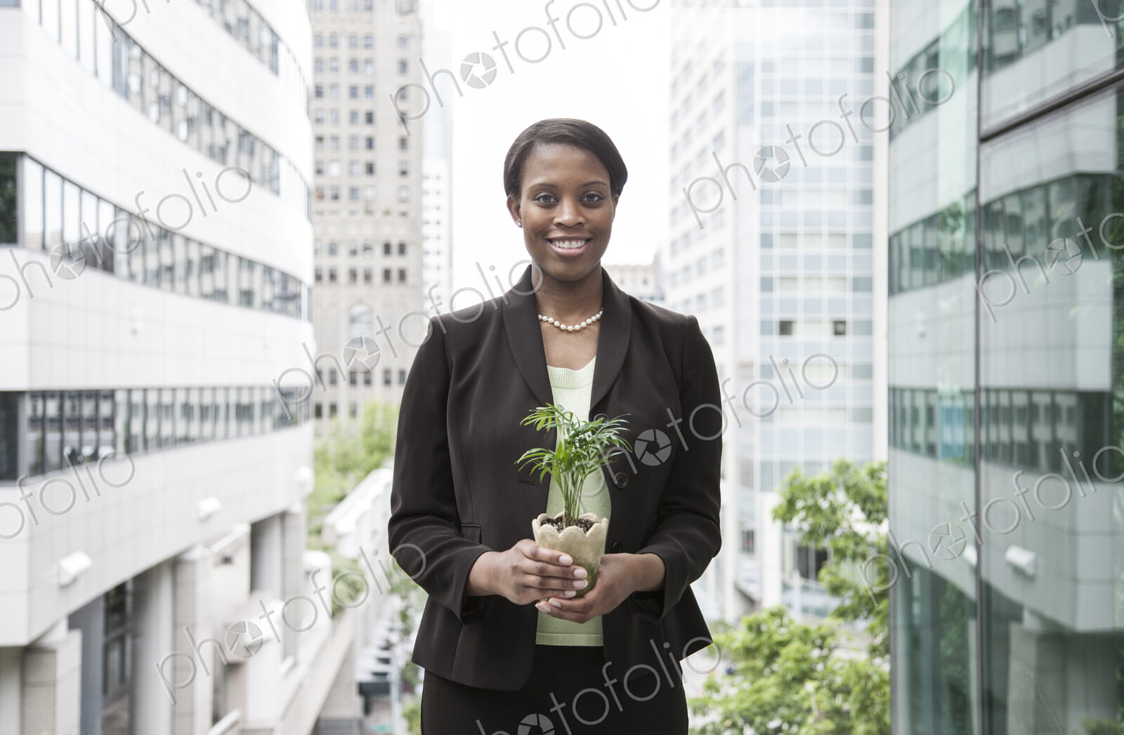 A businesswoman holding a small plant while stanidng next to a a large convention…