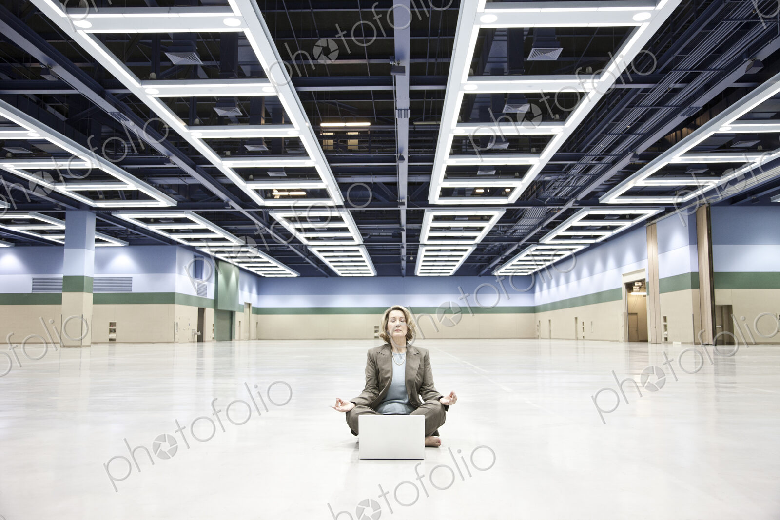 A businesswoman in a yoga pose with a laptop computer in the middle of a convention…