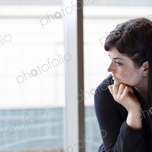 A businesswoman looking out a window at a convention center.
