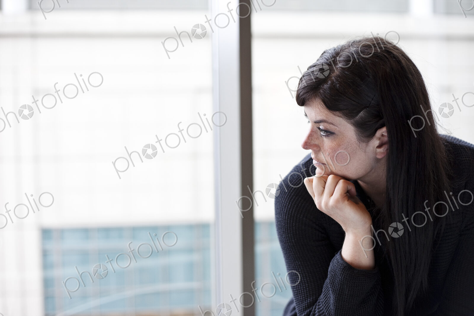 A businesswoman looking out a window at a convention center.