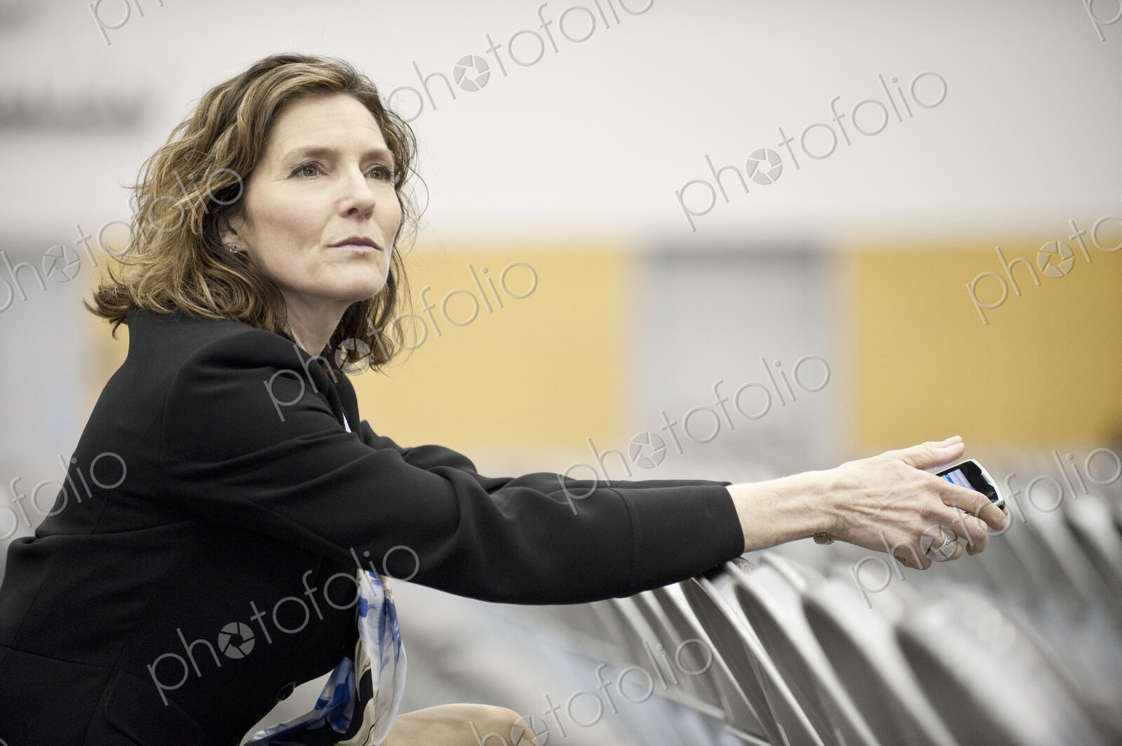A businesswoman sitting alone in a room full of chairs prior to a meeting in a…