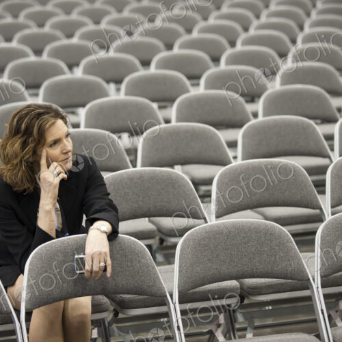 A businesswoman sitting alone in a room full of chairs prior to a meeting in a…