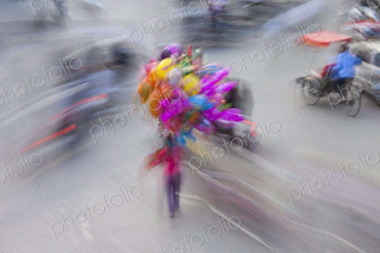 A busy street in Hanoi city, with motorscooter traffic and people with colourful balloons.