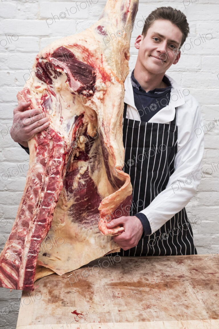 A butcher holding a carcass of spring lamb butchered and halved.