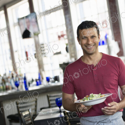 A cafe interior. A man in a waiter's apron serving a meal. A cafe interior. A man in a waiter's apron serving a meal.