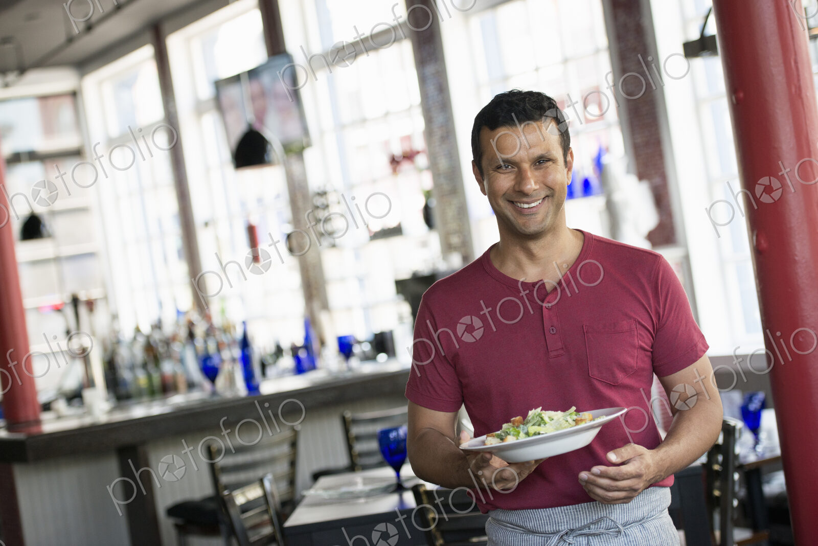A cafe interior. A man in a waiter’s apron serving a meal.