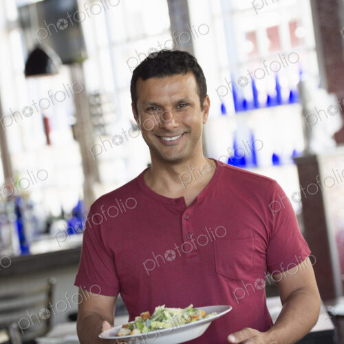 A cafe interior. A man in a waiter's apron serving a meal. A cafe interior. A man in a waiter's apron serving a meal.