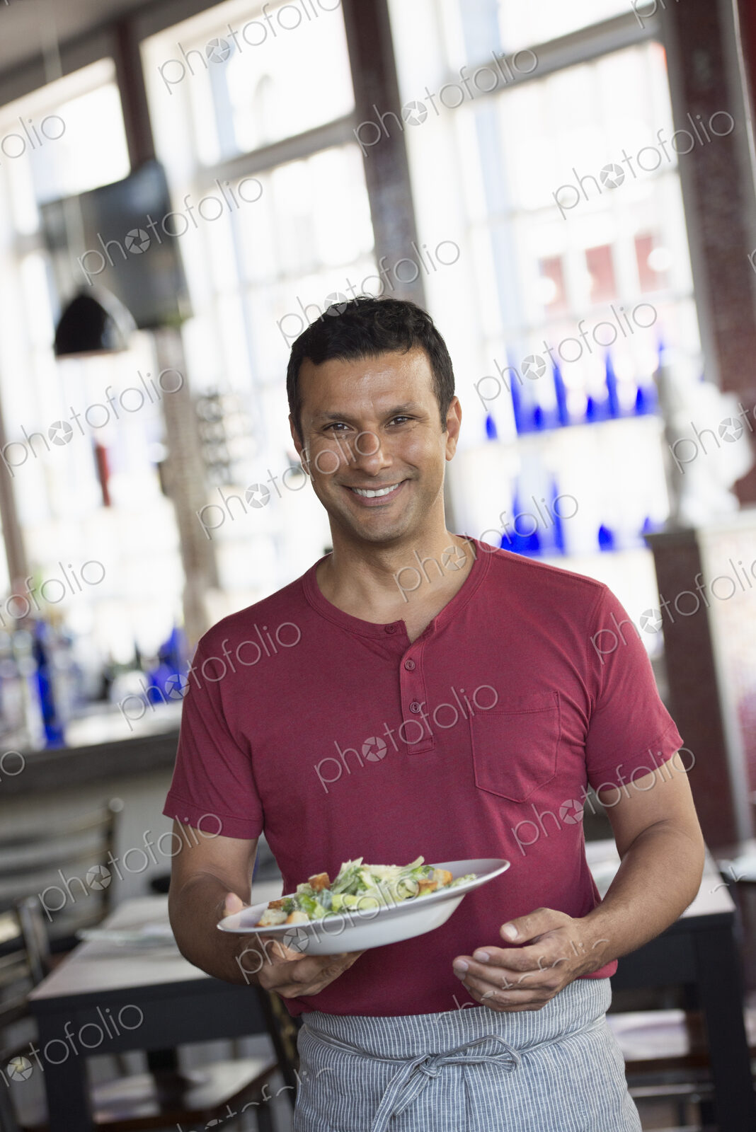 A cafe interior. A man in a waiter’s apron serving a meal.