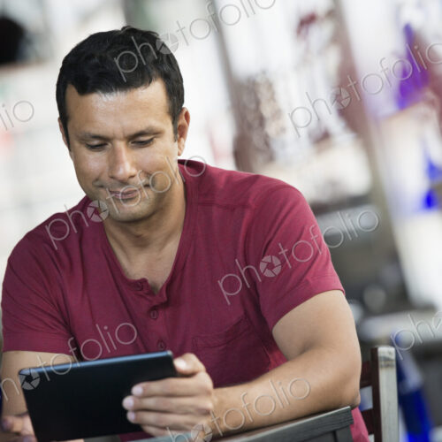A cafe interior. A man sitting using a digital tablet. A cafe interior. A man sitting using a digital tablet.