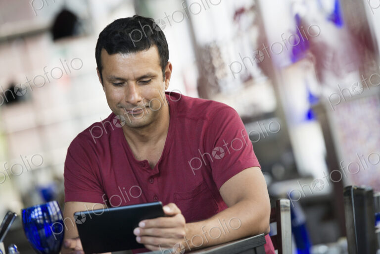 A cafe interior. A man sitting using a digital tablet.