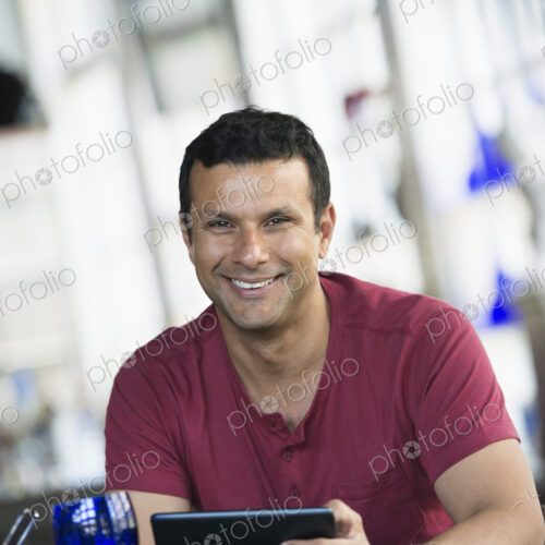 A cafe interior. A man sitting using a digital tablet. A cafe interior. A man sitting using a digital tablet.