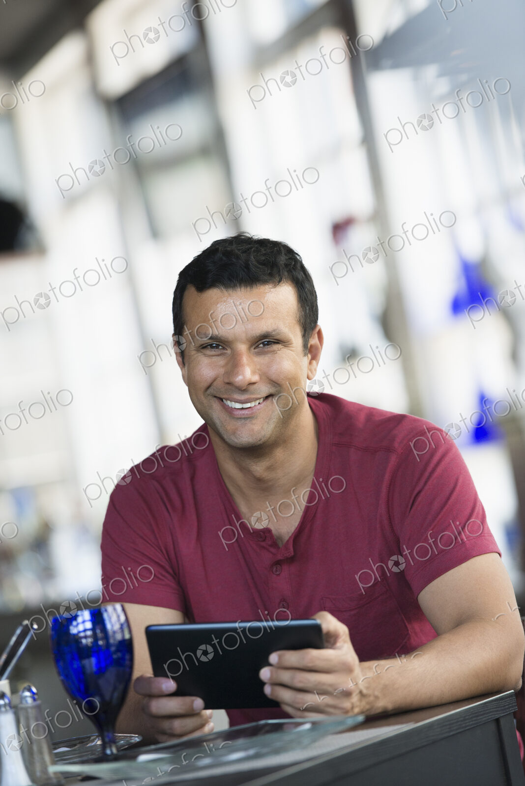 A cafe interior. A man sitting using a digital tablet.