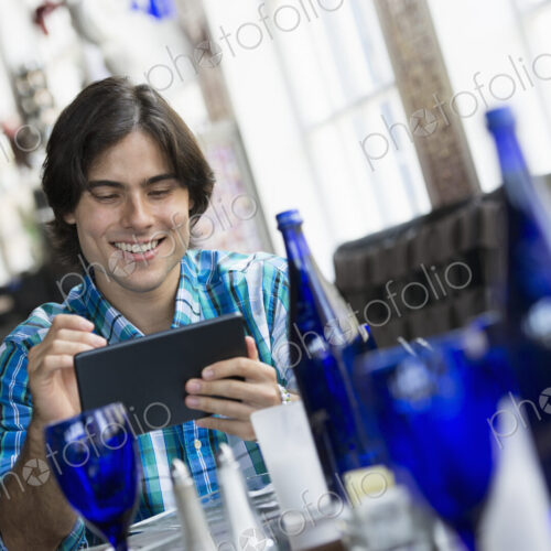 A cafe interior. A man sitting using a digital tablet.